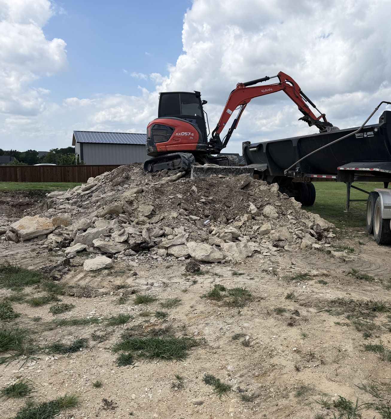 Mini excavator loading rock debris into a dump trailer