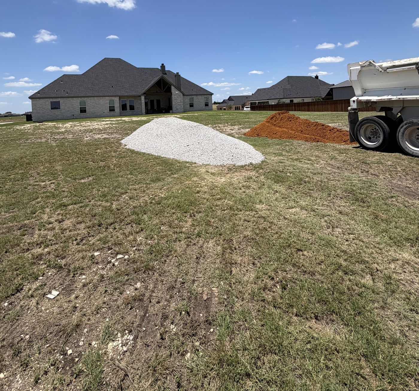 White rock and red dirt delivered behind a new home