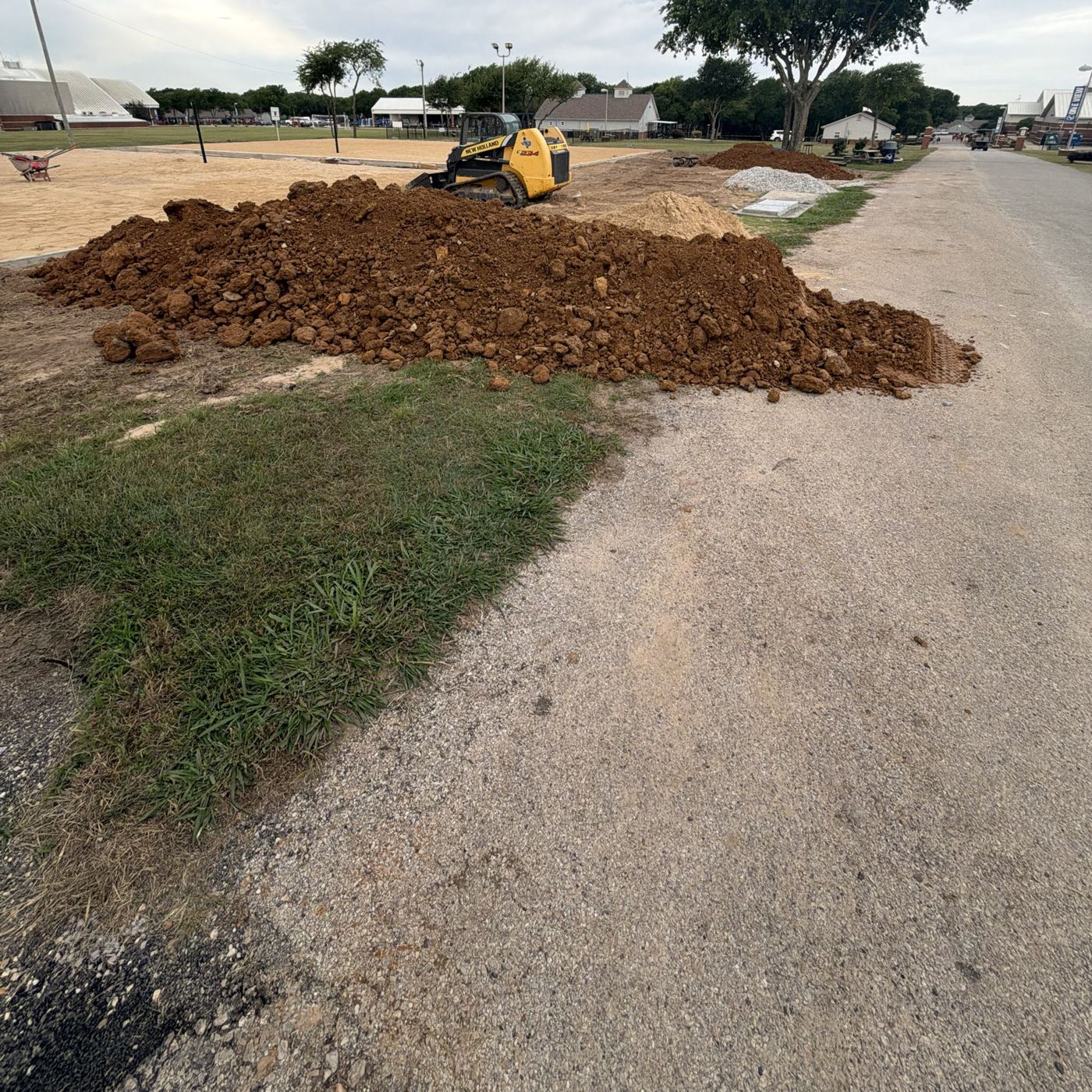 Skid steer spreading dirt next to a sand volleyball court