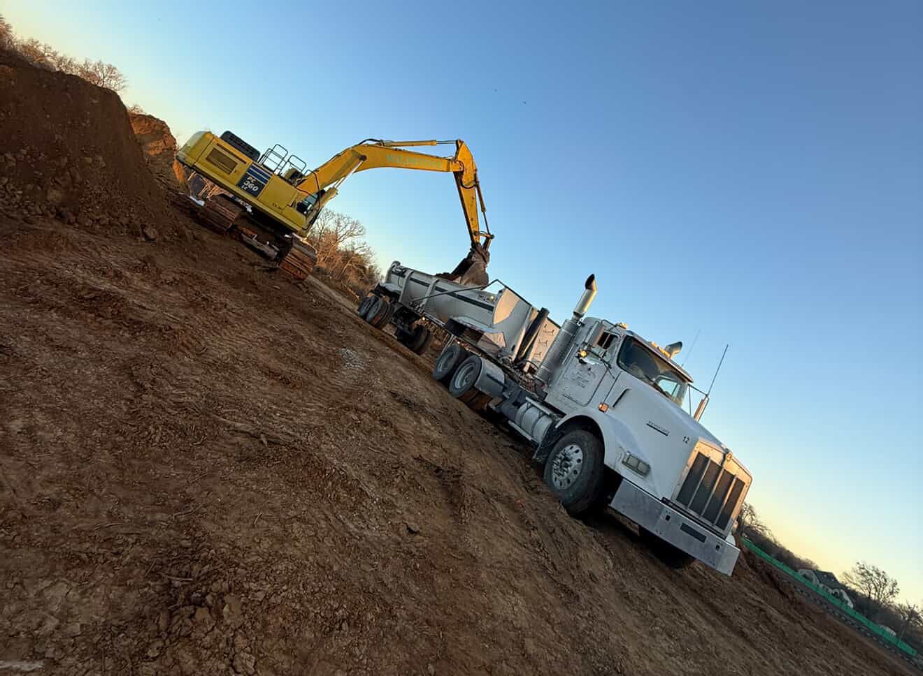 Excavator loading an end dump on a site