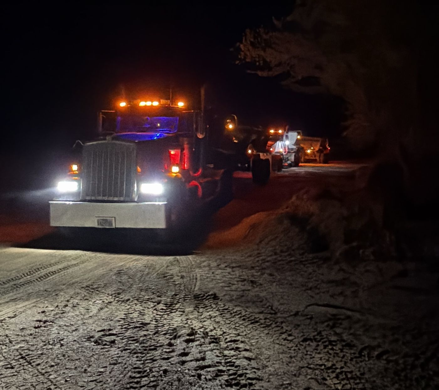 Dump trucks with lights on at night